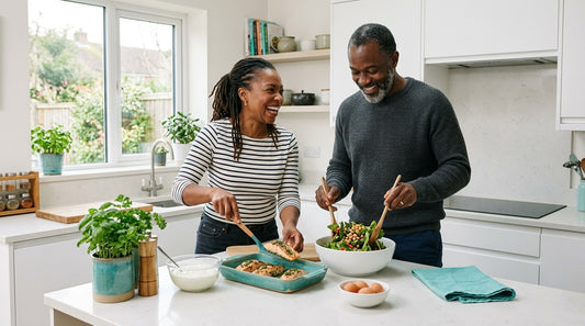 A couple in their fifties preparing a protein-rich meal of salmon and salad together in a bright modern kitchen